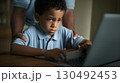 Boy learning on laptop with woman's support, showing importance of education in nurturing environment 130492453