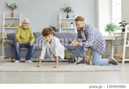 Child doing push-ups sport exercises at home with father and grandfather supporting him Child doing push-ups sport exercises at home with father and grandfather supporting him 130493060