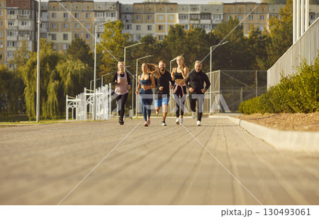 Group of happy motivated runners exercising together running on treadmill in stadium. 130493061