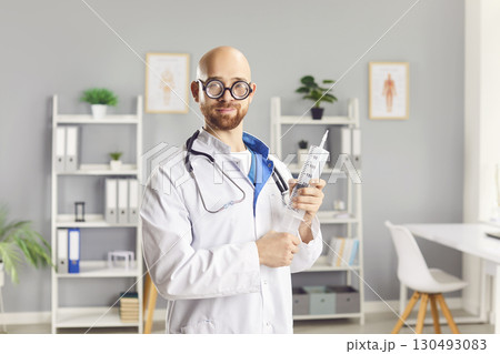 Funny Doctor Holding A Large Syringe In Clinic Funny Doctor Holding A Large Syringe In Clinic 130493083