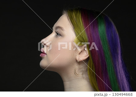 Profile of a young female model with perfect sensual lips and multi-colored strands of hair on a black background. Beautiful facial skin, augmentation of female lips, glamorous elegance. Profile of a young female model with perfect sensual lips and multi-colored strands of hair on a black background. Beautiful facial skin, augmentation of female lips, glamorous elegance. 130494668