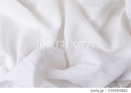 A fragment of crumpled white fabric as a background texture.Crumpled white linen or cotton fabric. A fragment of crumpled white fabric as a background texture.Crumpled white linen or cotton fabric. 130494862