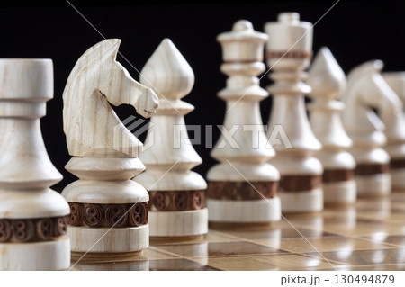 White chess pieces on a chess field. A puzzle game with tricky combinations that requires planning and thinking. 130494879