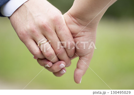 A man's hand with a wedding ring holds a woman's hand. 130495029