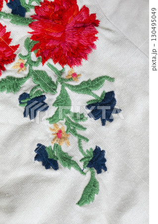 A piece of white cotton fabric with embroidered bright flowers. A piece of white cotton fabric with embroidered bright flowers. 130495049