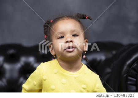 Portrait of a little playful African American girl on a dark background. 130495323