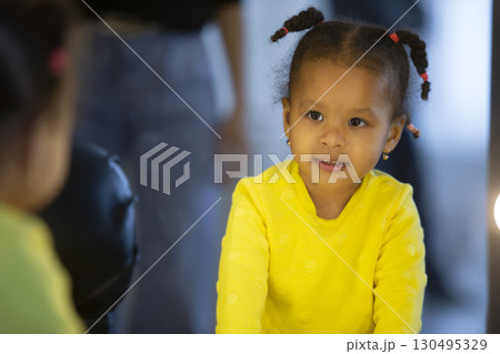 Little African American girl looks at her reflection in the mirror. 130495329