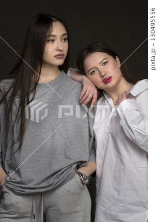 Two beautiful girls-friends on a dark background. Two beautiful girls-friends on a dark background. 130495556