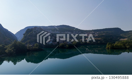 Serene morning reflections over a tranquil lake nestled between lush mountains 130495888