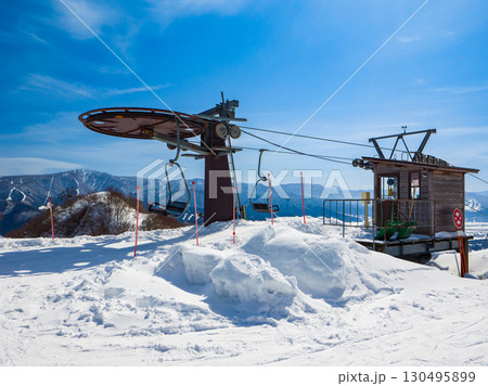 青空の下のスキーリフト降り場と遠くに望む冬の山並み (長野県、飯山市、戸狩温泉) 130495899
