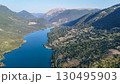 Serene panoramic view of a tranquil lake surrounded by lush hills at sunrise in a picturesque valley 130495903