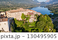 Charming village perched on a hillside overlooking tranquil waters in Italy during late afternoon light 130495905