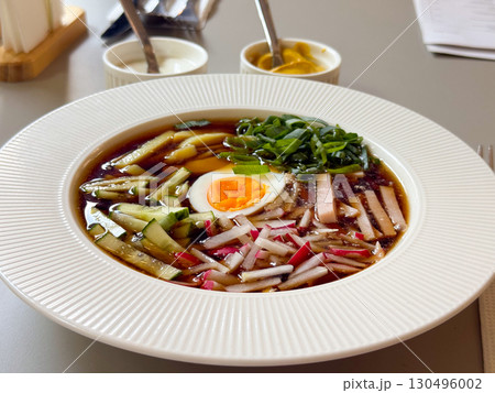Close-up of okroshka soup with cucumber, radish, egg, and sausage highlights detail. Traditional cuisine, summer refreshment, and cultural gastronomy symbolize heritage, health, and lifestyle Close-up of okroshka soup with cucumber, radish, egg, and sausage highlights detail. Traditional cuisine, summer refreshment, and cultural gastronomy symbolize heritage, health, and lifestyle 130496002