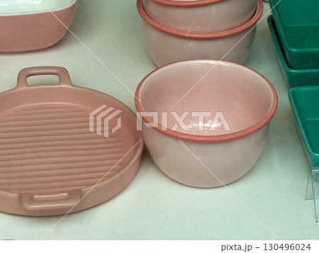 Ceramic tableware in soft pink and green tones displayed on a shop shelf. Kitchen equipment, dining utensils, and consumer goods symbolize household lifestyle and everyday domestic aesthetics. 130496024