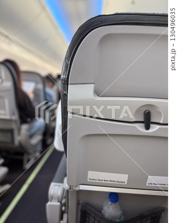 Aircraft cabin interior with passenger seat back and safety instructions. Aviation, travel, and passenger service equipment for flight safety and onboard comfort system. 130496035
