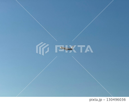Airplane flying in clear blue sky at high altitude with visible red tailfin. Aviation, transportation, speed, and global connectivity through air travel. 130496036