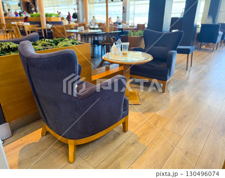 Two armchairs with round glass table and drinks in cafe. Hospitality, lifestyle and relaxation moments in public dining culture. Two armchairs with round glass table and drinks in cafe. Hospitality, lifestyle and relaxation moments in public dining culture. 130496074