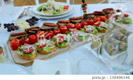 Gourmet appetizers and snacks arranged on wooden board, white ceramic plates, highlighting professional catering preparation for elegant restaurant dining experience 130496146