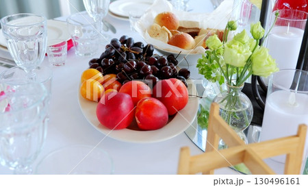 Elegantly arranged table displaying ripe cherries, plums, apricots, peaches surrounding crisp bread, delicate crystal glassware, and vibrant floral centerpiece Elegantly arranged table displaying ripe cherries, plums, apricots, peaches surrounding crisp bread, delicate crystal glassware, and vibrant floral centerpiece 130496161
