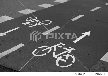 Black and white photo of bike lane with direction and bicycle markings. Symbolizing potential dangers of ignoring safety rules, the image highlights the consequences of unsafe cycling 130496634