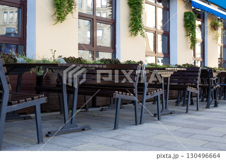Modern outdoor seating arrangement with benches and tables, accented by decorative planters. The minimalist design creates an inviting space for social gatherings in urban environments Modern outdoor seating arrangement with benches and tables, accented by decorative planters. The minimalist design creates an inviting space for social gatherings in urban environments 130496664