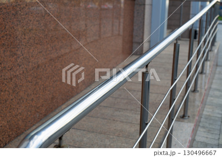Handrail on ramp designed for people with limited mobility, offering support for safe and comfortable access to public spaces. Feature ensures accessibility and independence in urban environment 130496667