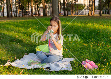 Little girl enjoying picnic in sunny park setting Little girl enjoying picnic in sunny park setting 130496697