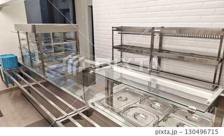 Modern stainless steel and glass cafeteria serving counter in industrial kitchen 130496715