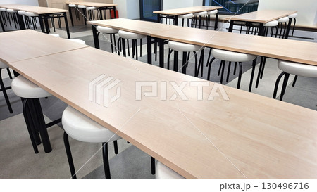 Empty classroom with wooden desks and white chairs in modern educational setting Empty classroom with wooden desks and white chairs in modern educational setting 130496716