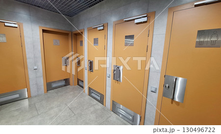 Public restroom interiors with multiple stall doors in modern design 130496722