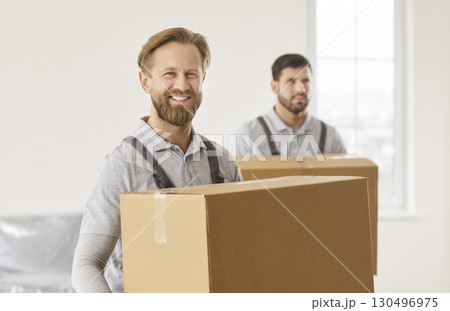 Men delivery workers holding carton boxes with belongings, working in moving company Men delivery workers holding carton boxes with belongings, working in moving company 130496975