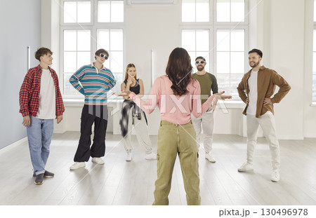 Female dance instructor leading group of young people in studio during hip hop choreography session. Female dance instructor leading group of young people in studio during hip hop choreography session. 130496978