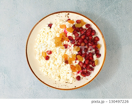 Granular fresh cottage cheese with pomegranate seeds and raisins on a sunny table, natural nutrition concept, healthy lifestyle advertising, baby food. Healthy breakfast with ingredients, menu for Granular fresh cottage cheese with pomegranate seeds and raisins on a sunny table, natural nutrition concept, healthy lifestyle advertising, baby food. Healthy breakfast with ingredients, menu for 130497226