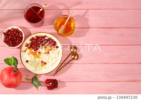Granular fresh cottage cheese with pomegranate seeds, raisins, honey and juice on a sunny table, detox diet and natural nutrition concept, healthy lifestyle advertising, baby food. Healthy breakfast Granular fresh cottage cheese with pomegranate seeds, raisins, honey and juice on a sunny table, detox diet and natural nutrition concept, healthy lifestyle advertising, baby food. Healthy breakfast 130497230
