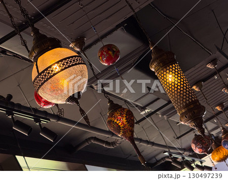 Mosaic lanterns with red and multicolored glass glowing in hanging arrangement. Traditional craft, cultural art, and heritage lighting symbolizing hospitality and vibrant decoration. Mosaic lanterns with red and multicolored glass glowing in hanging arrangement. Traditional craft, cultural art, and heritage lighting symbolizing hospitality and vibrant decoration. 130497239
