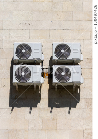 Four air conditioners are mounted on the wall. air conditioners are white. 130497426