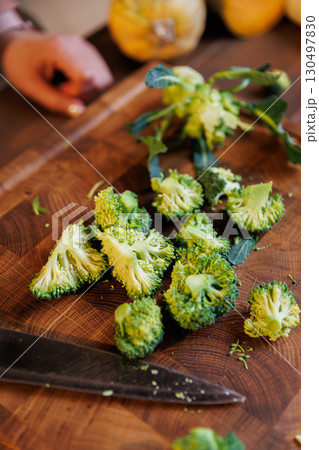Freshly cut broccoli florets on a wooden board with a kitchen knife, rustic cooking concept Freshly cut broccoli florets on a wooden board with a kitchen knife, rustic cooking concept 130497830