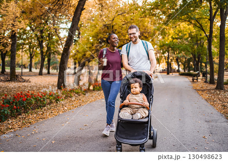 Mixed race couple walks their son's stroller through the park 130498623