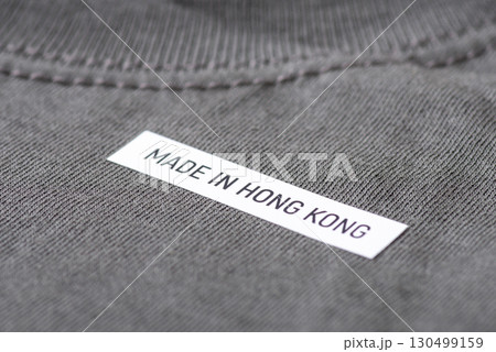 Close up of a t-shirt with inscription Made in Hong Kong. Producing clothes in Hong Kong concept Close up of a t-shirt with inscription Made in Hong Kong. Producing clothes in Hong Kong concept 130499159