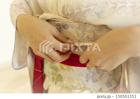 着物の帯を締める若い女性の手元の写真 130501351