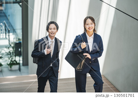 オフィスビルの階段を歩くスーツを着た若い男女 130501701
