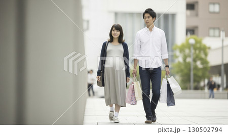 妊婦と夫がマタニティグッズの買い物帰りのシーン。 荷物は全部夫が持っている。 130502794