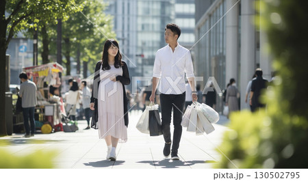 妊婦と夫がマタニティグッズの買い物帰りのシーン。 荷物は全部夫が持っている。 130502795