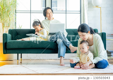 リビングでパソコンを見る若い家族 リビングでパソコンを見る若い家族 130503043
