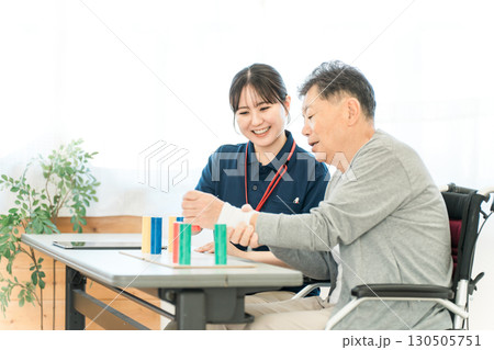 介護施設・リハビリ施設で働く作業療法士の職員とリハビリをするシニア男性 130505751