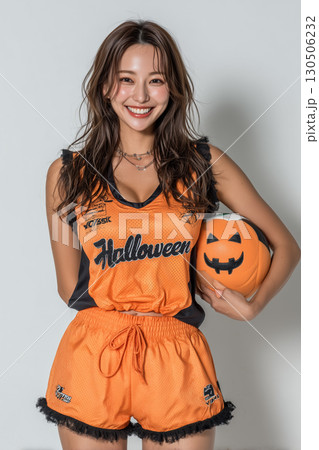 ハロウィンデザインのボールを持つ女性｜スポーツとイベントを融合した元気なイメージ 130506232