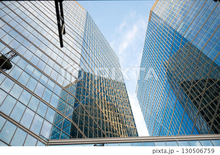 Modern glass skyscrapers reflecting blue sky in urban landscape Modern glass skyscrapers reflecting blue sky in urban landscape 130506759