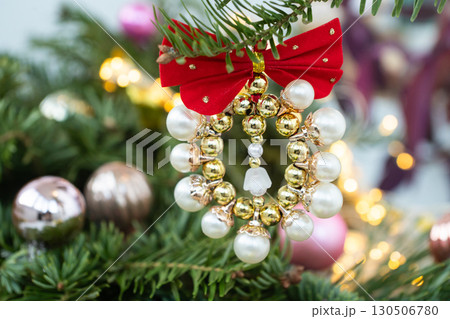 Festive christmas tree ornament with red bow and gold beads on pine branches Festive christmas tree ornament with red bow and gold beads on pine branches 130506780