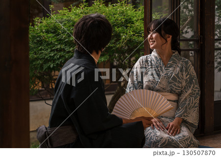 夕涼みに日本家屋の縁側に座る浴衣姿のアジア人カップル・夫婦 130507870