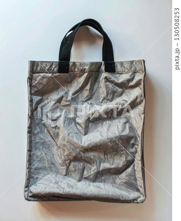 Silver Textured Shopping Bag with Black Handles on White Surface Close Up 130508253